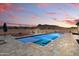 Beautifully tiled pool with a cozy outdoor seating area set against a colorful sunset at 5700 N 202Nd Ln, Litchfield Park, AZ 85340