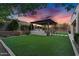 Expansive backyard with a pergola-covered outdoor kitchen and grill area surrounded by lush green lawn at 610 W Tonto Dr, Chandler, AZ 85248