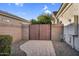 Gated side yard with brick-lined walkway to a closed gate flanked by verdant trees providing a sense of privacy at 610 W Tonto Dr, Chandler, AZ 85248