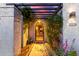 Inviting entryway featuring a decorative security gate, lush landscaping, and a charming pergola overhead at 6338 E Camelot Dr, Mesa, AZ 85215