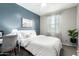 Stylish bedroom with a blue accent wall, white bedding, and a dedicated workspace by the window at 1153 E Muirwood Dr, Phoenix, AZ 85048
