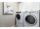 Functional laundry room with modern washer and dryer, complemented by overhead cabinets for storage at 1153 E Muirwood Dr, Phoenix, AZ 85048
