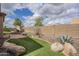 Large backyard features an outdoor brick fireplace, turf, rocks, a block fence, and desert landscaping at 1154 E Kramer Cir, Mesa, AZ 85203