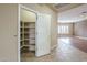 Walk-in pantry featuring ample shelving for storage; view of living space with hardwood flooring and natural light at 1154 E Kramer Cir, Mesa, AZ 85203