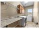 A functional laundry room features built-in cabinets, ample countertop space, and modern washer and dryer units at 12839 W Rincon Ct, Sun City West, AZ 85375