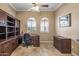 Office with a traditional dark wood desk, built-in shelving, and two arched windows illuminating the space at 12839 W Rincon Ct, Sun City West, AZ 85375