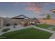 Well-manicured backyard with lush green grass, desert landscaping, and a cozy seating area at 14372 W Aster Dr, Surprise, AZ 85379