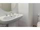 Powder room with a white pedestal sink and toilet with round mirror at 14372 W Aster Dr, Surprise, AZ 85379