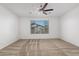 Well-lit bedroom with a ceiling fan and plush carpet, complemented by a view from the window at 14372 W Aster Dr, Surprise, AZ 85379