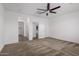 Spacious bedroom with carpet, featuring a ceiling fan and access to a closet and bathroom at 14372 W Aster Dr, Surprise, AZ 85379