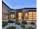 Modern home with desert landscaping, featuring a glass garage door and front door, and elegant lighting at 14455 N Adero Canyon Dr, Fountain Hills, AZ 85268