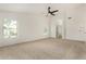 Bright bedroom featuring plush carpeting, ceiling fan, and large window for natural light, and en-suite bathroom at 16510 W Baden Ave, Goodyear, AZ 85338