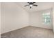 A bright bedroom with neutral carpet, a ceiling fan and a window allowing natural light at 16510 W Baden Ave, Goodyear, AZ 85338