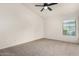 Carpeted bedroom with a ceiling fan, base molding, and large window at 16510 W Baden Ave, Goodyear, AZ 85338