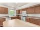 Well-lit kitchen with wood cabinets, white oven, dishwasher, and center island, creating a practical cooking space at 16510 W Baden Ave, Goodyear, AZ 85338