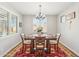 Bright dining room featuring modern chandelier, red rug, and natural light from the large window with plantation shutters at 18438 W Brookwood Dr, Goodyear, AZ 85338