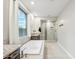 Bright main bathroom featuring a soaking tub, glass shower, and large window with natural light at 18438 W Brookwood Dr, Goodyear, AZ 85338