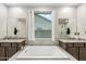 Spacious main bathroom featuring dual sinks, soaking tub, and large window with bright, natural light at 18438 W Brookwood Dr, Goodyear, AZ 85338