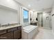 Relaxing main bathroom featuring a soaking tub, dual vanities, and a walk-in glass shower at 18438 W Brookwood Dr, Goodyear, AZ 85338