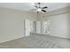 Neutral bedroom with carpet, a ceiling fan, and open doorways to the hallway and another room at 20802 N 74Th Ln, Glendale, AZ 85308