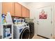 Well-lit laundry room featuring wooden cabinets, a washer/dryer and neutral tile flooring at 21752 E Domingo Rd, Queen Creek, AZ 85142