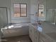 Spa-like bathroom with a soaking tub, glass-enclosed shower, and sleek white vanity with dual sinks and mirrors at 24134 N 172Nd Ave, Surprise, AZ 85387