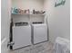 Bright laundry room with side-by-side washer/dryer, shelf, and decorative Laundry sign at 24408 W Ripple Rd, Buckeye, AZ 85326
