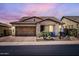Charming single-story home with a two-car garage, desert landscaping, and a tiled roof under a beautiful sunset sky at 26978 N 74Th Ln, Peoria, AZ 85383