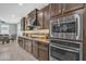 Modern kitchen features granite countertops, stainless steel appliances, tile backsplash, and dark wood cabinetry at 3690 E Blue Spruce Ln, Gilbert, AZ 85298