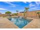 Backyard pool with a waterfall, palm trees, cacti, and stone accents under a blue sky at 3690 E Blue Spruce Ln, Gilbert, AZ 85298