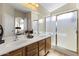 Bathroom featuring double sinks, a large mirror, and a glass-enclosed shower, enhancing the room's bright and airy ambiance at 40729 W Coltin Way, Maricopa, AZ 85138