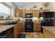 Well-equipped kitchen includes wood cabinetry, black appliances, and stylish countertops at 40729 W Coltin Way, Maricopa, AZ 85138