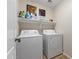 Functional laundry room with modern washer and dryer, plus shelving for storage at 40729 W Coltin Way, Maricopa, AZ 85138
