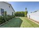 A backyard with artificial grass and tall green shrubs lining the gray concrete wall at 4402 E Montecito Ave, Phoenix, AZ 85018