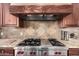 Kitchen range featuring stainless steel Wolf brand appliances and custom wood hood at 7013 E Summit Trail Cir, Mesa, AZ 85207