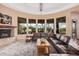 Elegant living room featuring a cozy fireplace, large windows, and comfortable leather seating at 7013 E Summit Trail Cir, Mesa, AZ 85207