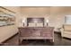 Beautiful main bedroom with a dark wood bed frame, wooden floors, and a cozy armchair at 7013 E Summit Trail Cir, Mesa, AZ 85207