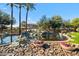 Scenic community pond with a rock waterfall feature, mature trees, and colorful flower planters at 705 W Queen Creek Rd # 1201, Chandler, AZ 85248