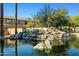 Community pond with a natural rock waterfall feature and mature landscaping around the water's edge at 705 W Queen Creek Rd # 1201, Chandler, AZ 85248