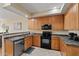 This kitchen features wooden cabinets, black appliances, and tiled floors for a functional and stylish space at 705 W Queen Creek Rd # 1201, Chandler, AZ 85248