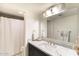 Bright bathroom with dark cabinets, white marble countertop, large mirror, and a shower with white curtain at 7930 E Arlington Rd # 8, Scottsdale, AZ 85250