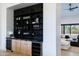 Stylish bar area with custom shelving, marble countertop, wine coolers, and view into the modern living room at 9238 E Palm Tree Dr, Scottsdale, AZ 85255