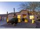 Well-lit single-story home featuring a three-car garage and desert landscaping at dusk at 9238 E Palm Tree Dr, Scottsdale, AZ 85255