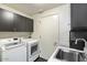 Functional laundry room with modern washer, dryer, sink, and ample storage in sleek cabinets at 1040 E Osborn Rd # 203, Phoenix, AZ 85014