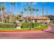 Inviting entrance with manicured landscaping, a charming fountain, and swaying palm trees under a clear blue sky at 11515 N 91St St # 142, Scottsdale, AZ 85260