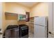 Laundry room with modern washer and dryer, a refrigerator, and storage shelving at 12572 W Jasmine Trl, Peoria, AZ 85383