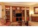 Living room featuring custom built-in shelves, a glass coffee table, and comfortable leather seating at 12572 W Jasmine Trl, Peoria, AZ 85383