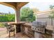 An outdoor kitchen offers a built-in grill, bar seating, and stone accents at 12572 W Jasmine Trl, Peoria, AZ 85383