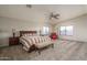 Bright bedroom featuring a ceiling fan, neutral walls, and a cozy red armchair with an ottoman at 14406 N 129Th Ave, El Mirage, AZ 85335