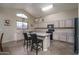 Functional kitchen featuring an island with seating, light wood cabinetry, and modern appliances at 14406 N 129Th Ave, El Mirage, AZ 85335